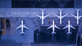 Six airplanes sitting on a dark blue tarmac