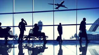 Travelers in an airport lounge with airplane taking off