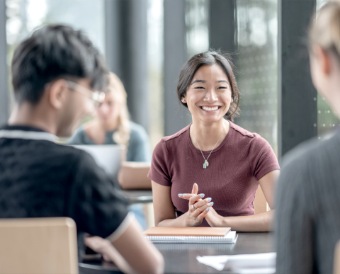 Lady at a table meeting with people, smiling