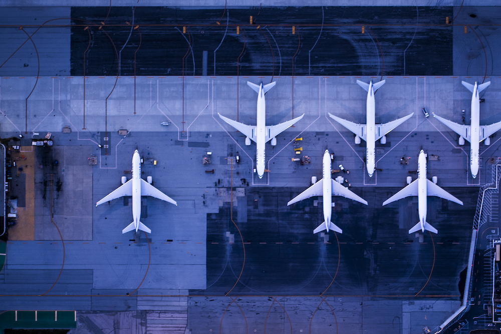 Six airplanes sitting on a dark blue tarmac
